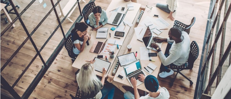 Employees collaborating in a conference room using connected devices.